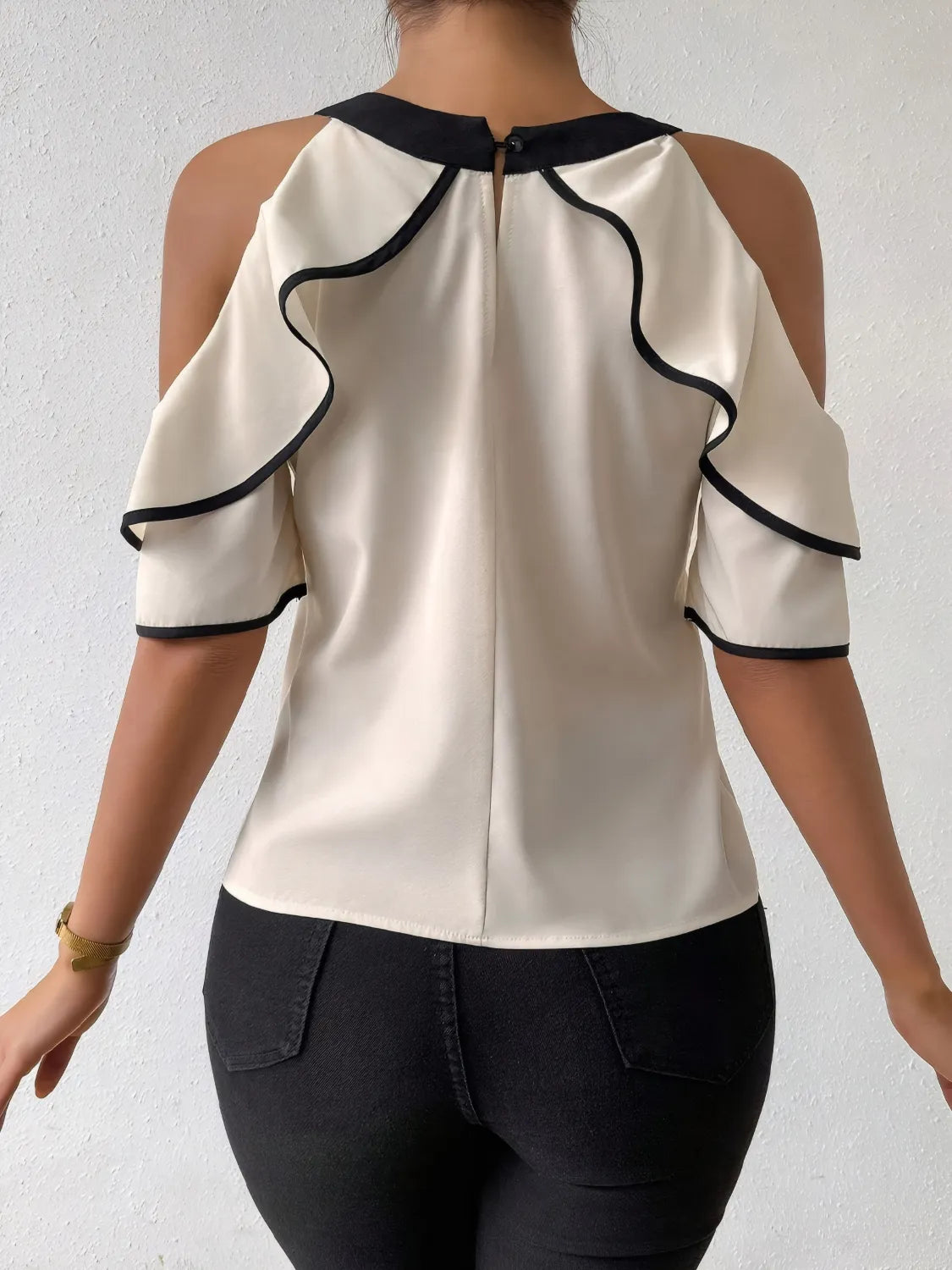Back view of a black and white ruffle blouse featuring elegant ruffle details and open shoulders