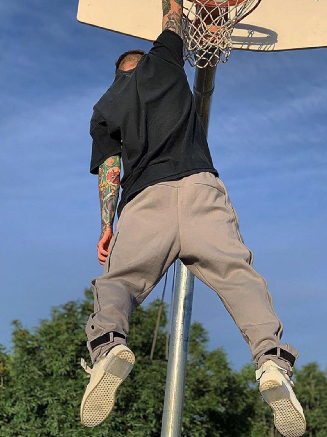 Athlete wearing comfortable men's pants while dunking a basketball outdoors