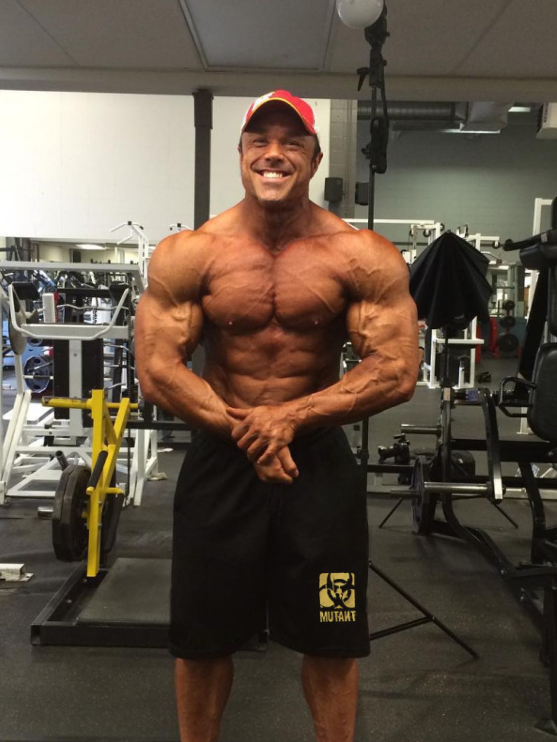 Muscular man wearing affordable men's gym shorts posing in a fitness gym setting