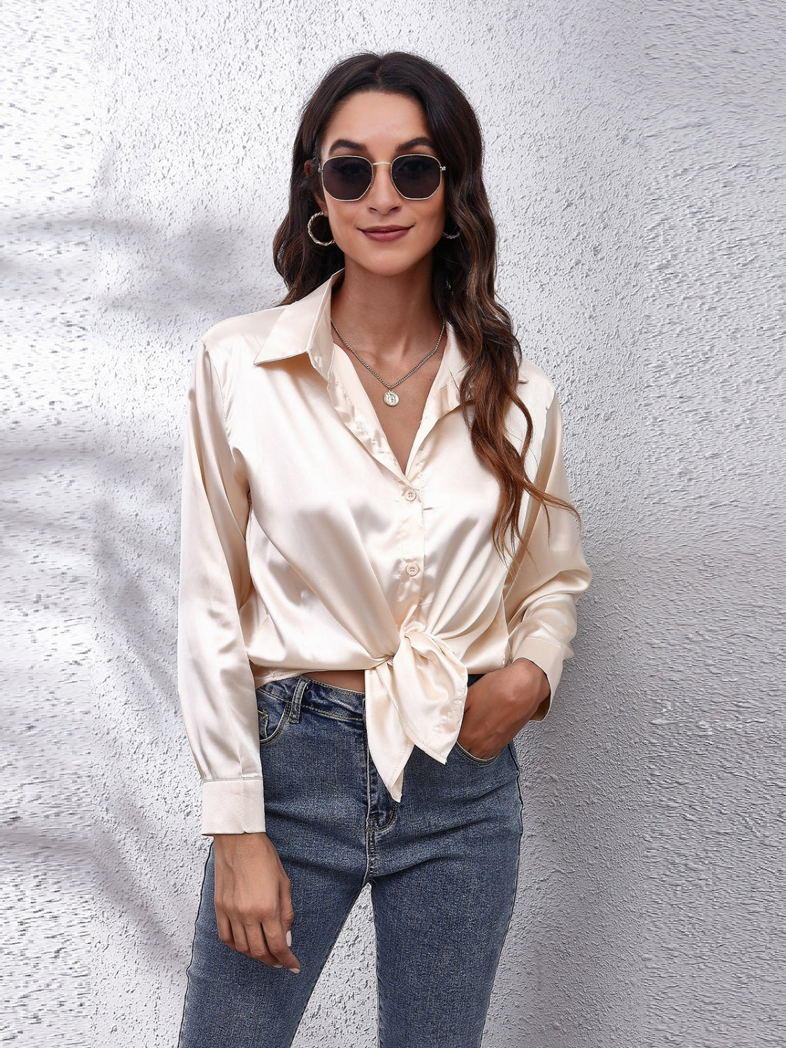 Trendy model wearing an affordable long sleeve shirt in silk with denim jeans and sunglasses