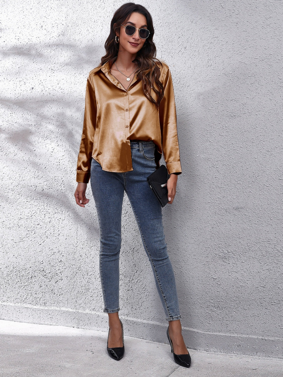 Stylish woman in a satin brown affordable long sleeve shirt paired with blue jeans and heels