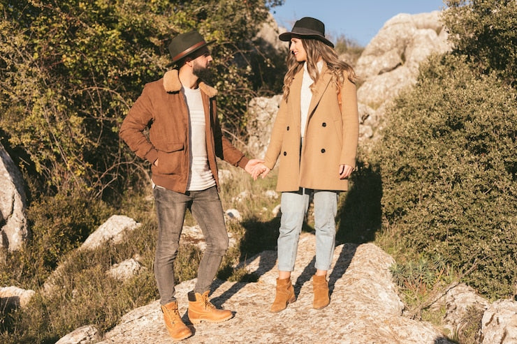 Couple wearing stylish outerwear on a rocky path with nature, featuring comfortable high quality shirts